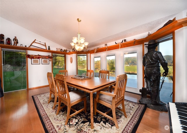 dining space with wood-type flooring, vaulted ceiling, and a notable chandelier