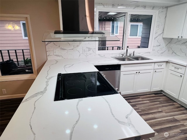 kitchen with stovetop, white cabinetry, sink, and range hood