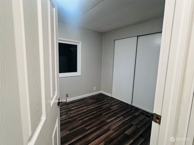 unfurnished bedroom with dark hardwood / wood-style flooring and a closet