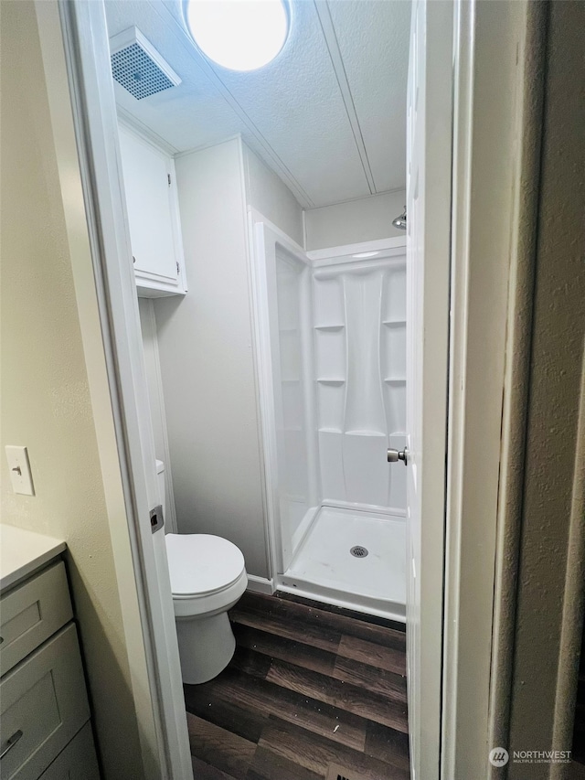 bathroom featuring vanity, a shower, hardwood / wood-style flooring, toilet, and a textured ceiling