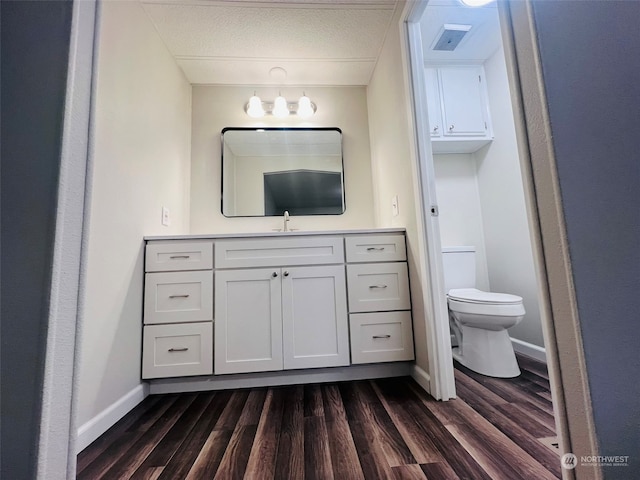 bathroom with vanity, toilet, wood-type flooring, and a textured ceiling