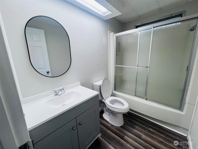 full bathroom featuring shower / bath combination with glass door, hardwood / wood-style floors, vanity, and toilet