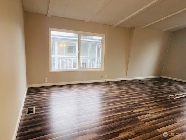 unfurnished room featuring beamed ceiling and dark hardwood / wood-style floors