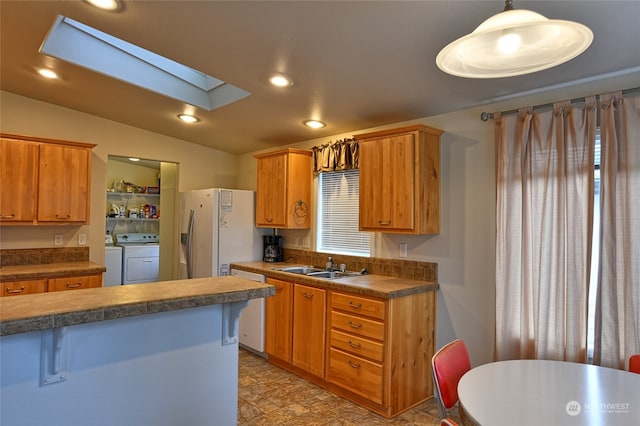 kitchen with lofted ceiling with skylight, white appliances, sink, hanging light fixtures, and separate washer and dryer