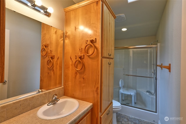 bathroom featuring vanity, toilet, and a shower with door