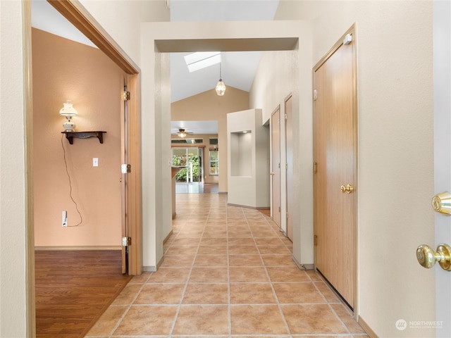 hall featuring lofted ceiling with skylight and light hardwood / wood-style flooring