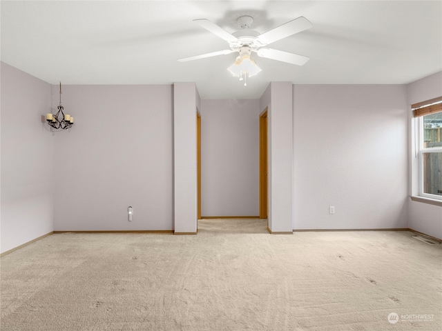 carpeted spare room with ceiling fan with notable chandelier