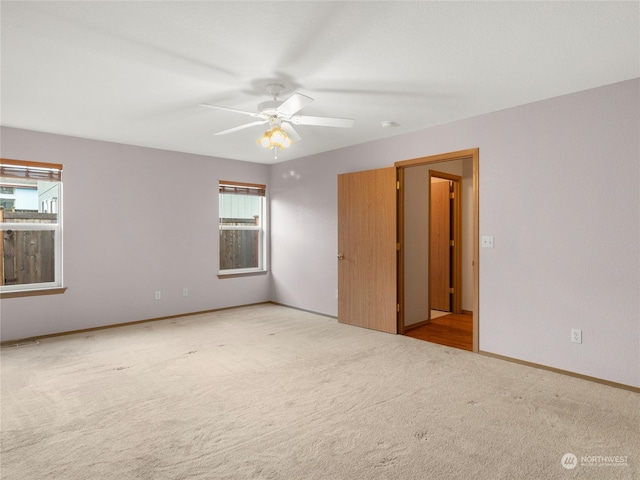 carpeted spare room featuring ceiling fan and a wealth of natural light