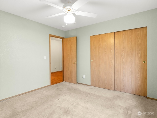 unfurnished bedroom featuring light carpet, a closet, and ceiling fan