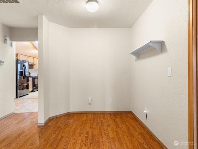 spare room featuring light wood-type flooring and a textured ceiling