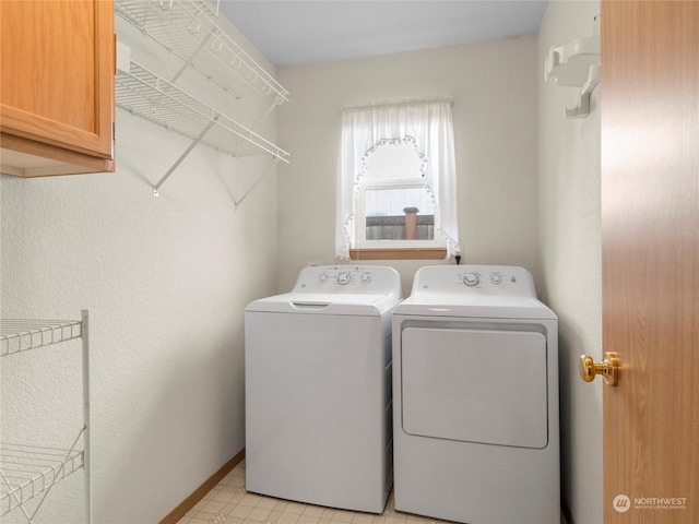 clothes washing area featuring separate washer and dryer and cabinets