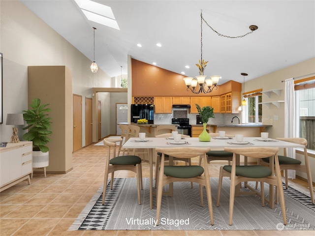 kitchen featuring high vaulted ceiling, black appliances, sink, a skylight, and a chandelier