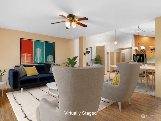 living room with wood-type flooring and ceiling fan with notable chandelier