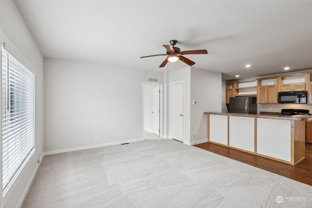 kitchen with stainless steel refrigerator, light carpet, kitchen peninsula, and ceiling fan