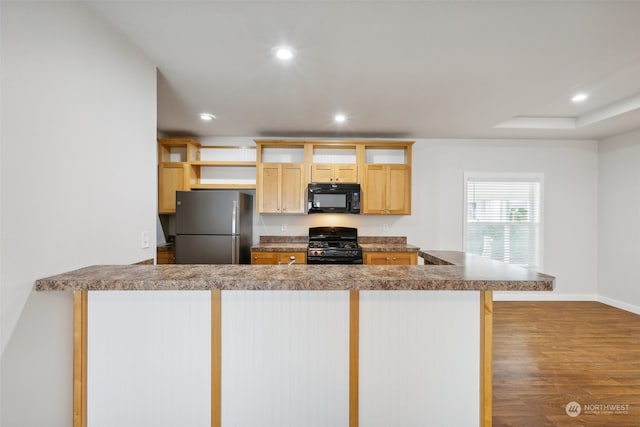 kitchen featuring a kitchen bar, black appliances, light brown cabinetry, dark hardwood / wood-style flooring, and kitchen peninsula