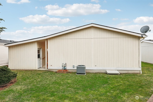 rear view of property with a lawn and cooling unit