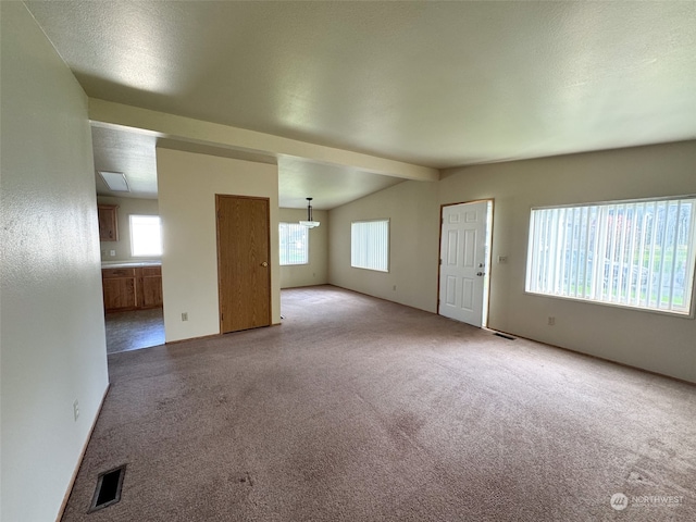 unfurnished living room with a textured ceiling, lofted ceiling with beams, and light carpet