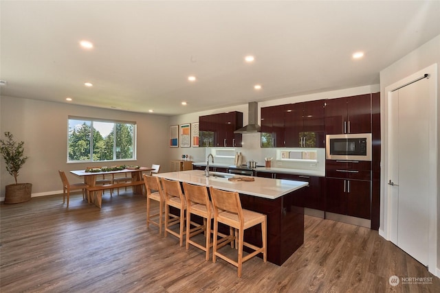 17726 142nd Ave E Unit 9, Puyallup, WA 98374 - kitchen featuring wall chimney exhaust hood, stainless steel microwave, a sink, modern cabinets, and a kitchen island with sink