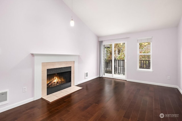 unfurnished living room with dark hardwood / wood-style floors, high vaulted ceiling, and a tiled fireplace