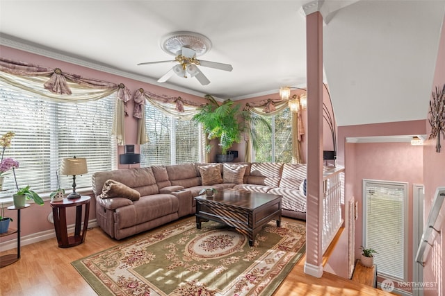 living area with baseboards, light wood-style flooring, ornamental molding, and a ceiling fan