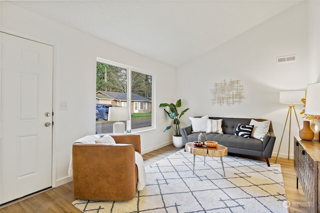 living room with light hardwood / wood-style flooring and vaulted ceiling