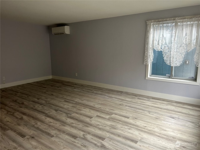 spare room with light hardwood / wood-style flooring and an AC wall unit