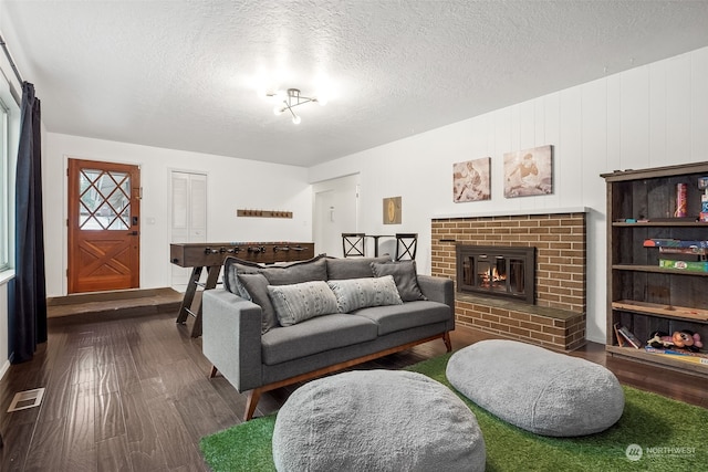 living room with a fireplace, a textured ceiling, and hardwood / wood-style flooring