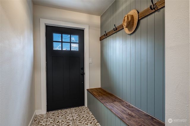 mudroom with wood walls and light tile patterned floors