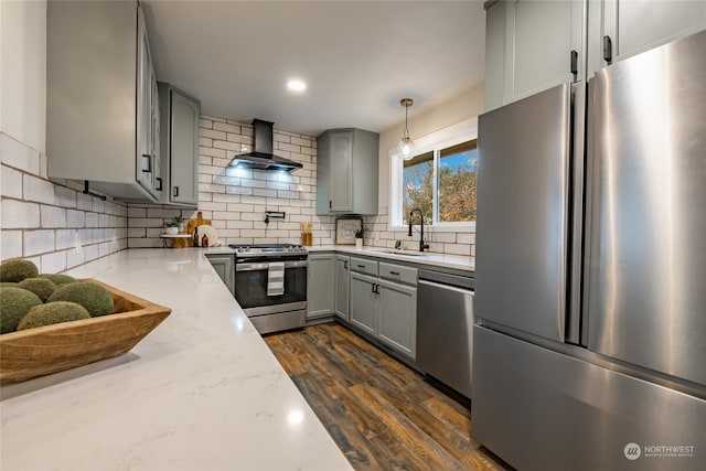 kitchen with wall chimney exhaust hood, stainless steel appliances, sink, dark hardwood / wood-style floors, and hanging light fixtures