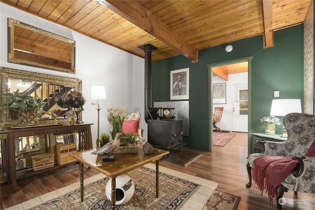 sitting room with beamed ceiling, hardwood / wood-style floors, a wood stove, and wooden ceiling