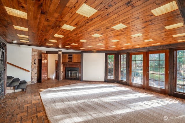 unfurnished living room featuring a fireplace, wooden ceiling, french doors, and a healthy amount of sunlight