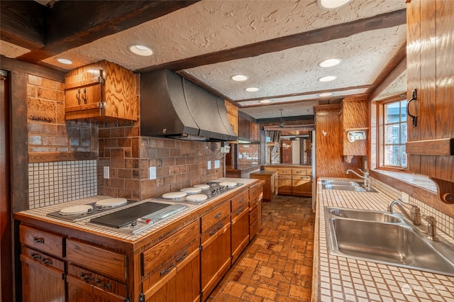 kitchen with tile counters, exhaust hood, a textured ceiling, and sink