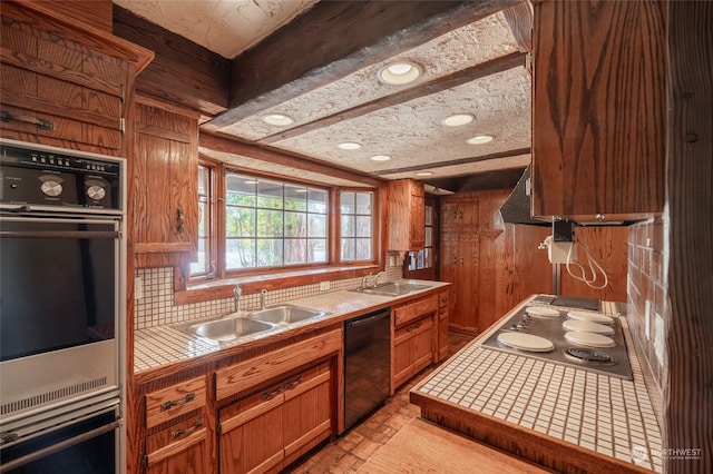 kitchen featuring tile countertops, stainless steel appliances, wooden walls, and sink