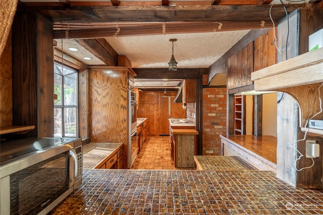 kitchen featuring kitchen peninsula, beam ceiling, and stainless steel appliances