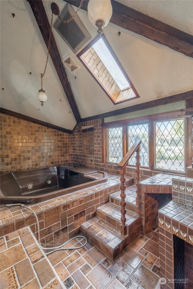 interior space with vaulted ceiling with skylight, brick wall, and a wealth of natural light