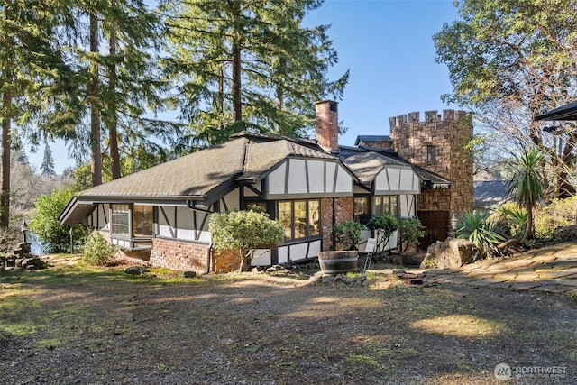 exterior space featuring a sunroom, a chimney, stone siding, and stucco siding