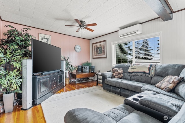 living room with ceiling fan, beamed ceiling, a wall unit AC, crown molding, and hardwood / wood-style flooring