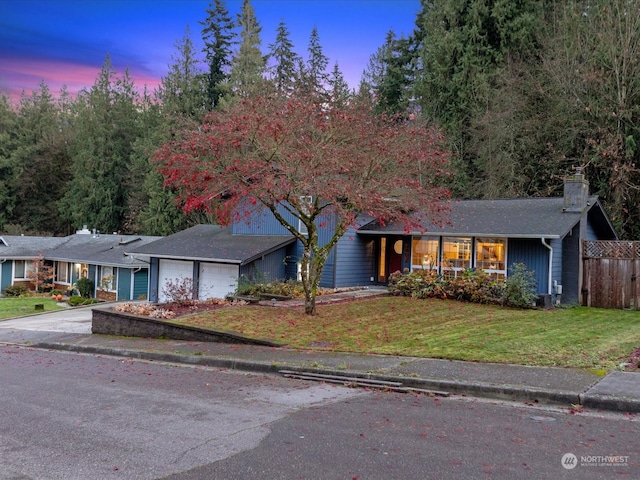 ranch-style house featuring a garage and a lawn