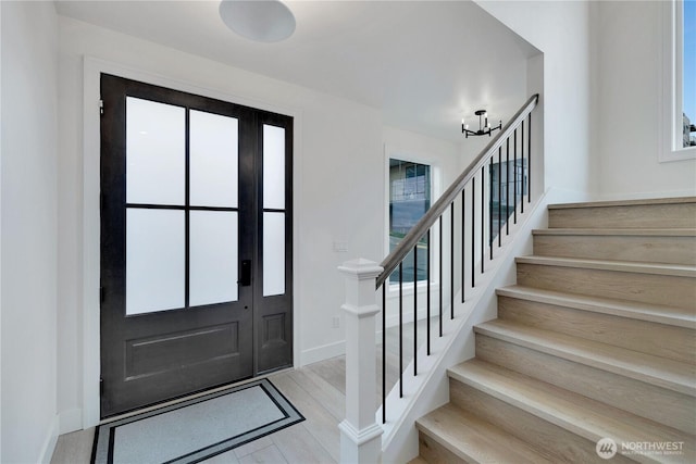 entrance foyer featuring a chandelier, baseboards, and stairs