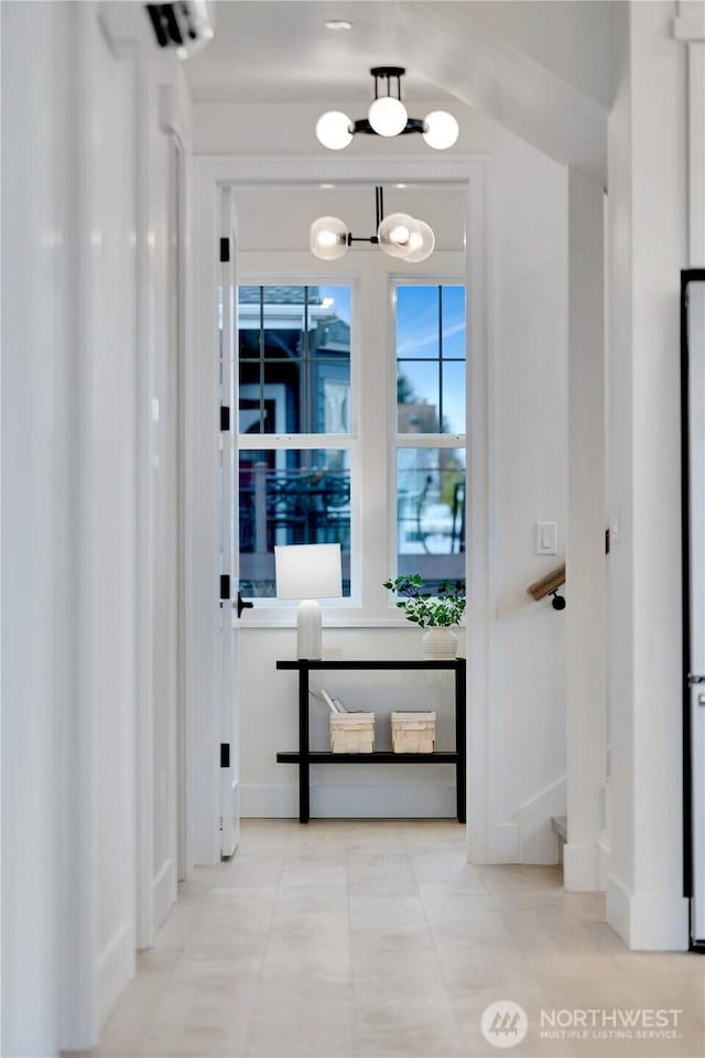 entryway featuring an inviting chandelier, baseboards, and tile patterned flooring