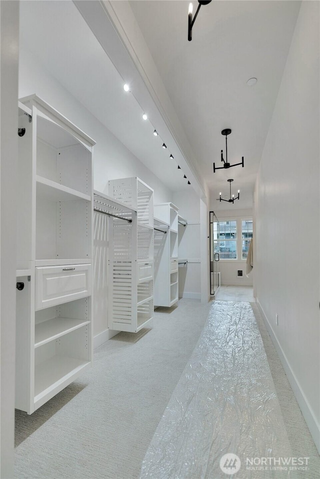 walk in closet with a chandelier and carpet flooring