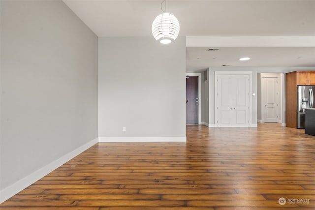 spare room featuring dark wood-type flooring and an inviting chandelier