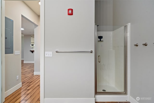 bathroom featuring electric panel, wood-type flooring, and a shower with shower door