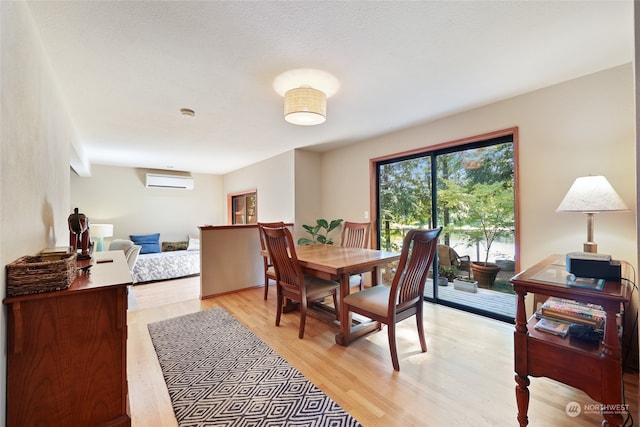 dining area featuring an AC wall unit and light wood-type flooring