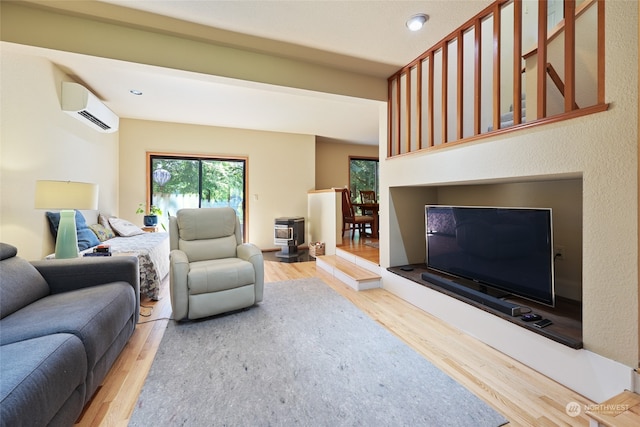 living room featuring hardwood / wood-style floors, a wood stove, and a wall mounted AC