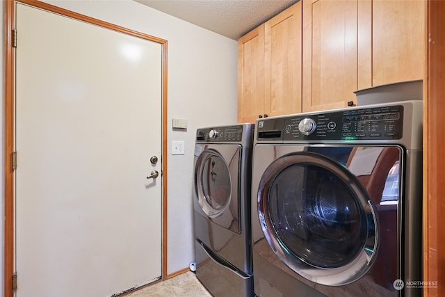 clothes washing area with cabinets, a textured ceiling, and washing machine and clothes dryer