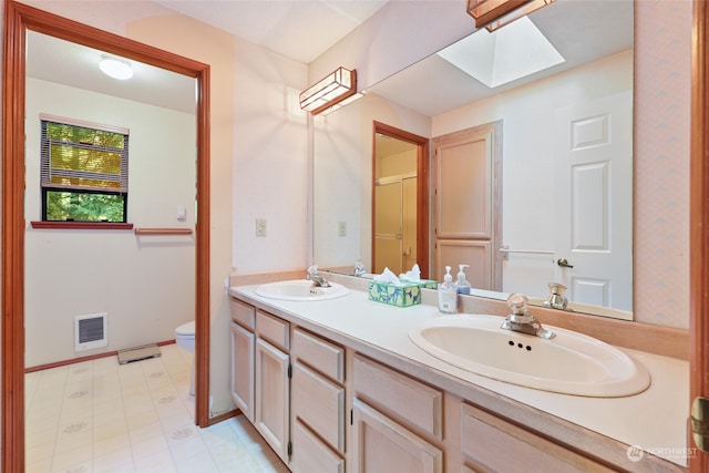 bathroom featuring vanity, a skylight, and toilet