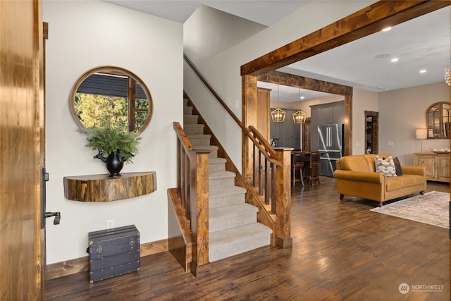 stairs featuring wood-type flooring and an inviting chandelier