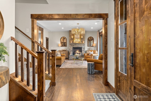 entrance foyer featuring an inviting chandelier, hardwood / wood-style flooring, and a stone fireplace