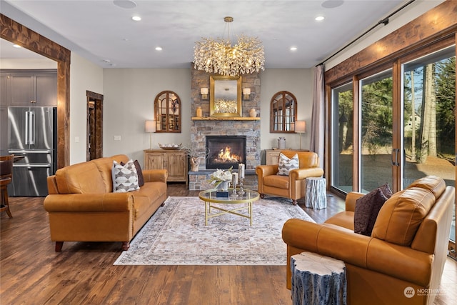 living room with a stone fireplace, dark wood-type flooring, and a chandelier